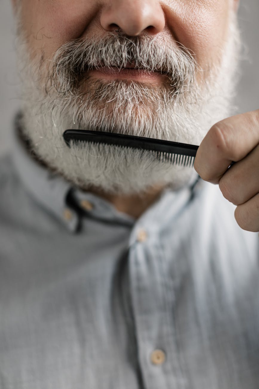 close up photo of elderly man combing his beard
