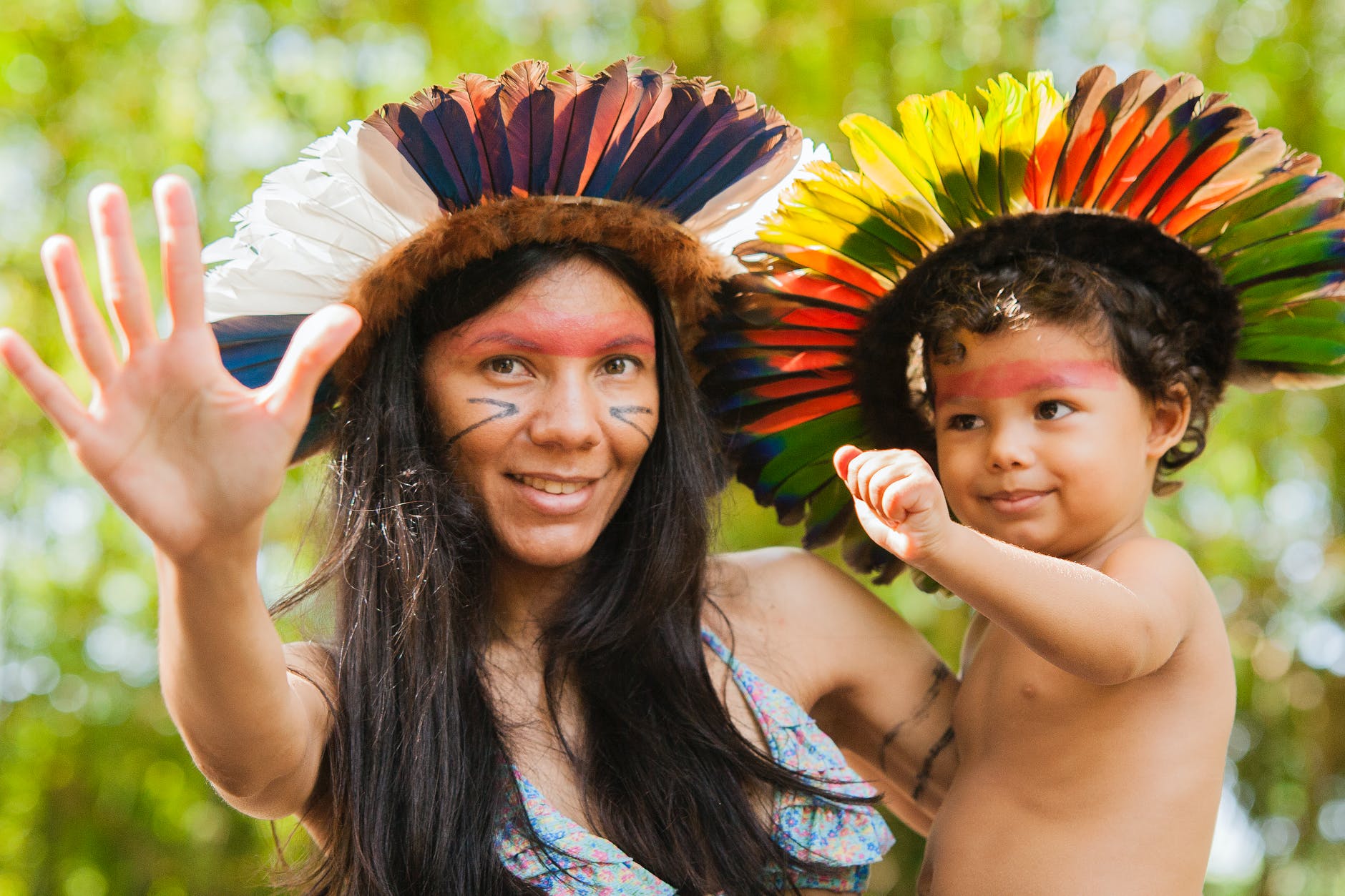 mother and child with face paint and headgear doing hand sign