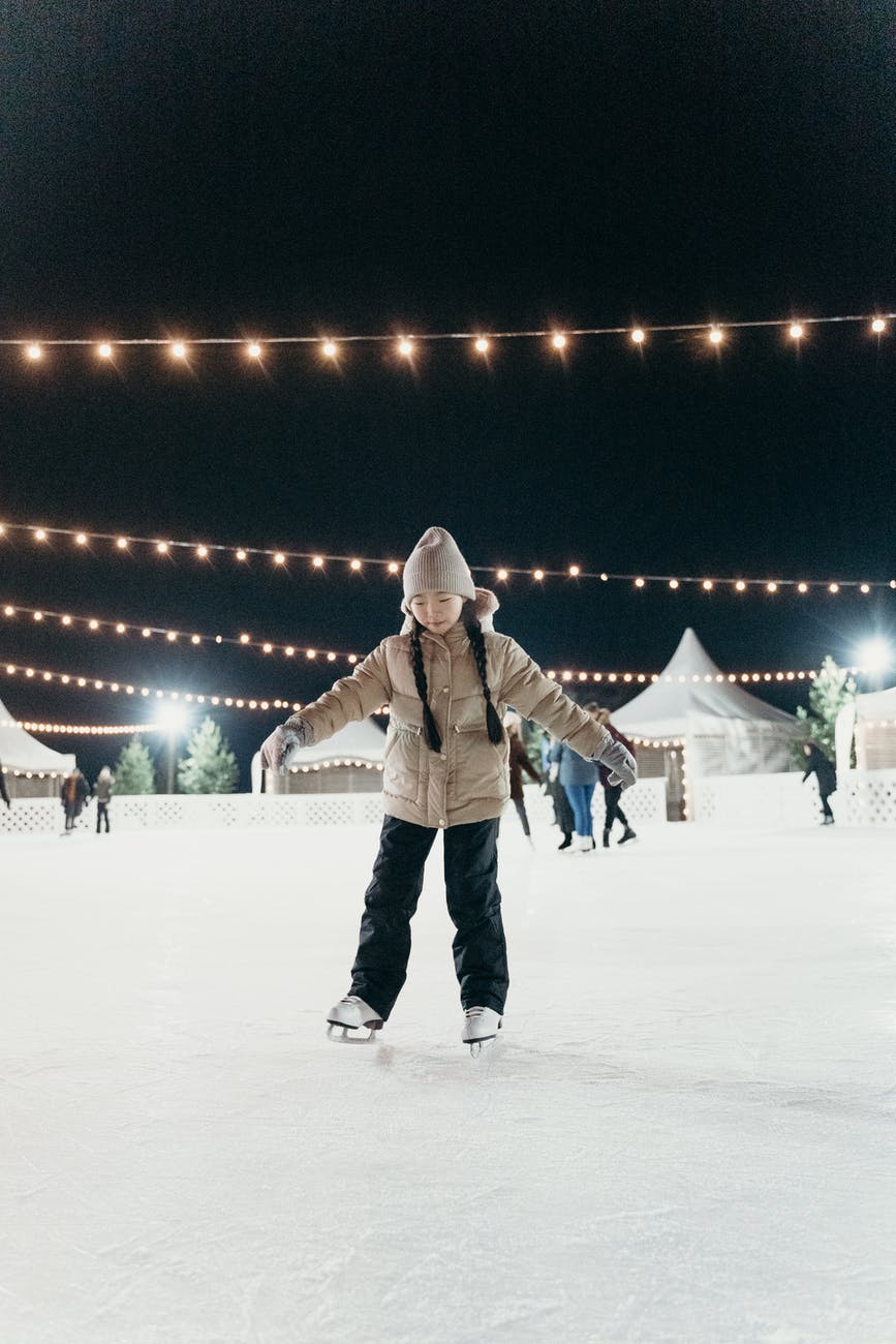 a girl wearing brown dawn jacket skating on ice rink
